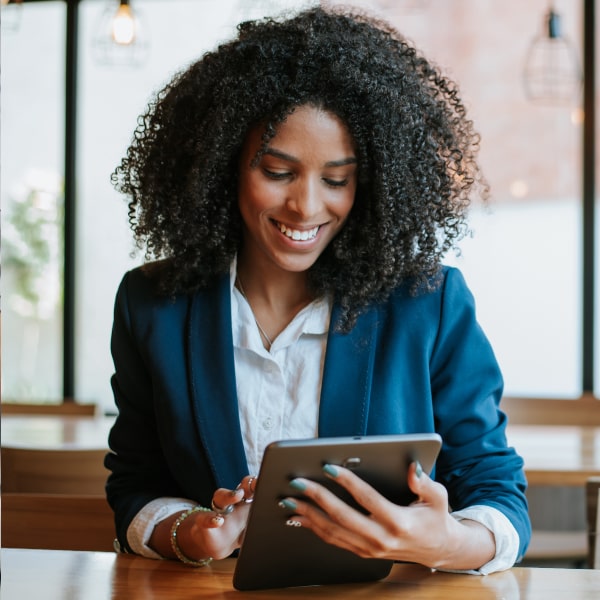 A curly girl with a tablet in her hands is smiling