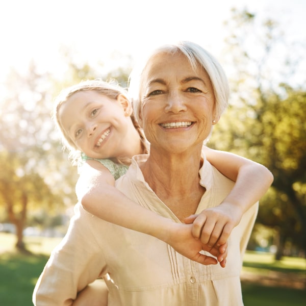 A girl and her grandmother are smiling while hugging