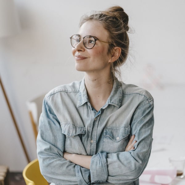 A girl in a denim shirt and glasses is smiling