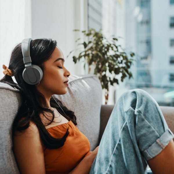A girl in headphones sits on a sofa