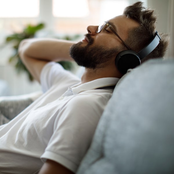 A guy in headphones is lying on a sofa