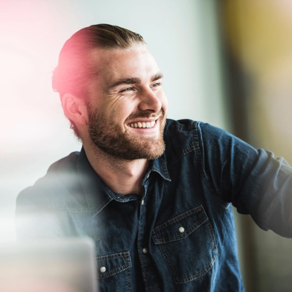 A young man with a beard is smiling
