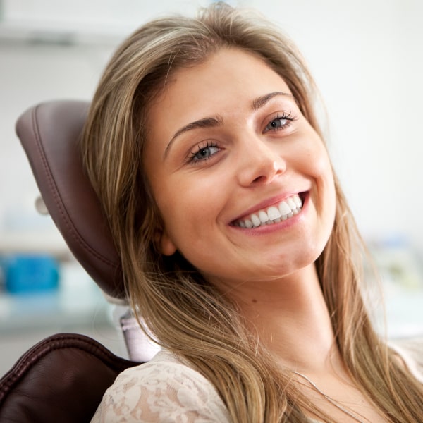 The girl smiles in the dental chair
